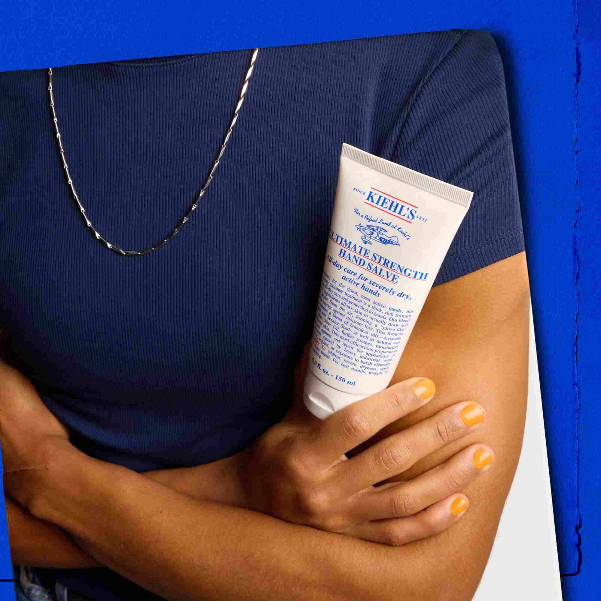 Modelo sosteniendo un tubo de Kiehl's Ultimate Strength Hand Salve