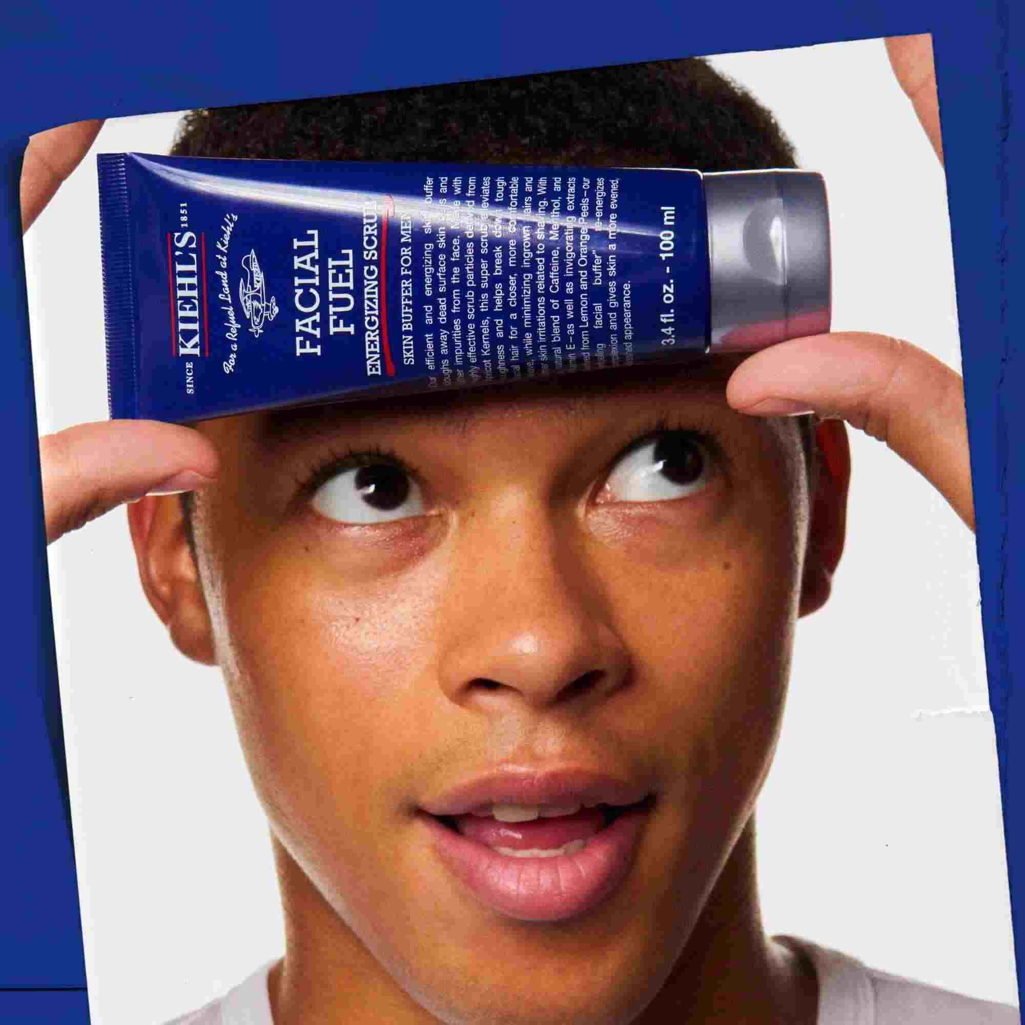 Facial Fuel Energizing Scrub sostenido en la mano, mostrando su uso.