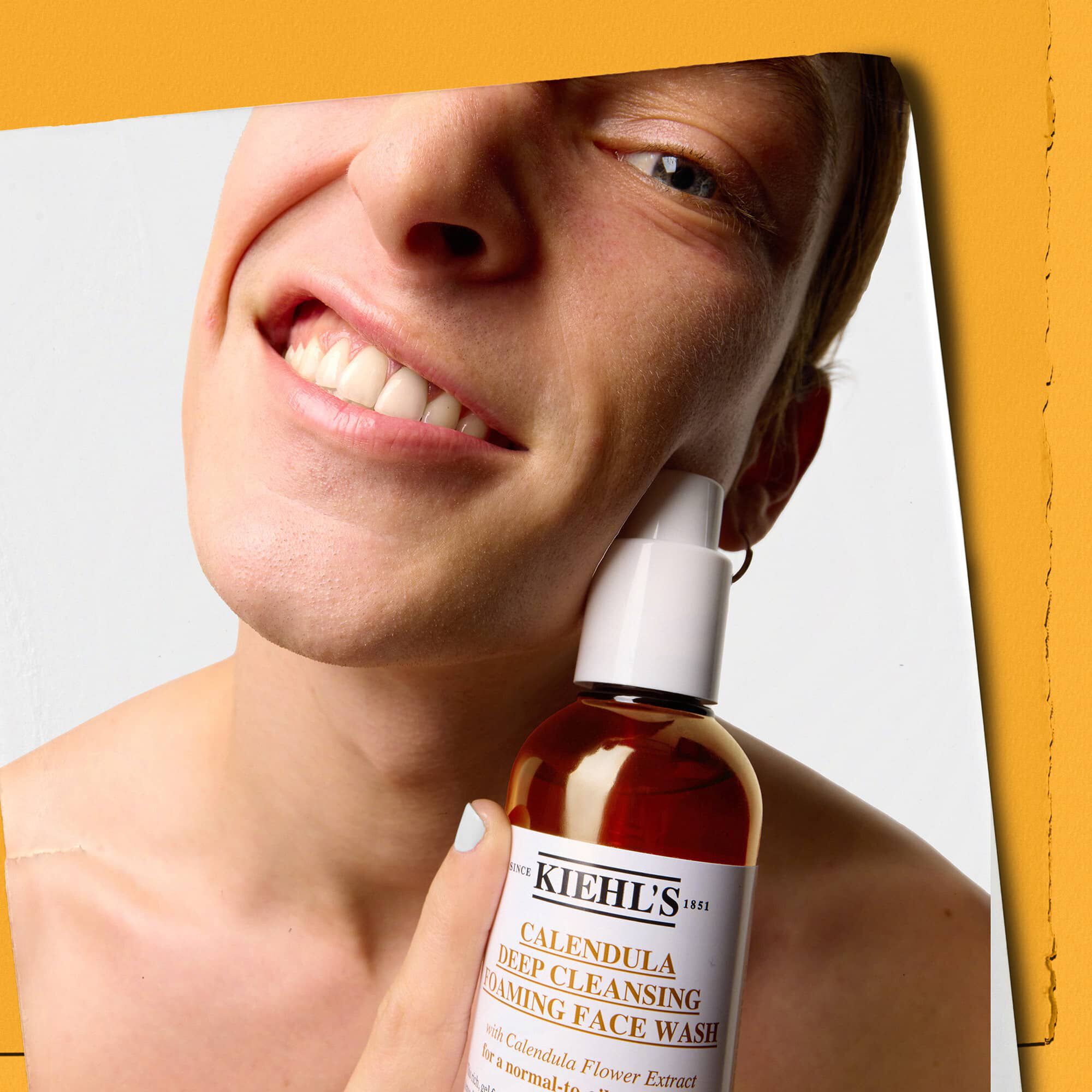 Modelo sosteniendo un frasco de Kiehl's Calendula Deep Cleaning Foaming Face Wash