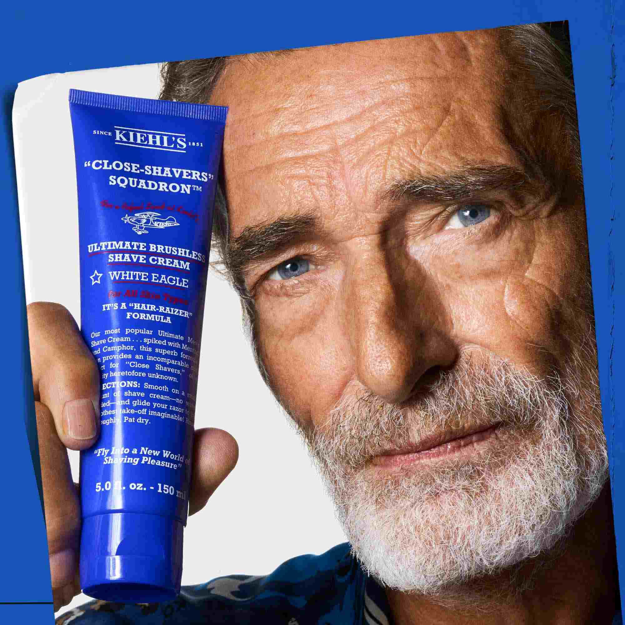 Un hombre sosteniendo un tubo de Ultimate Brushless Shave Cream White Eagle.