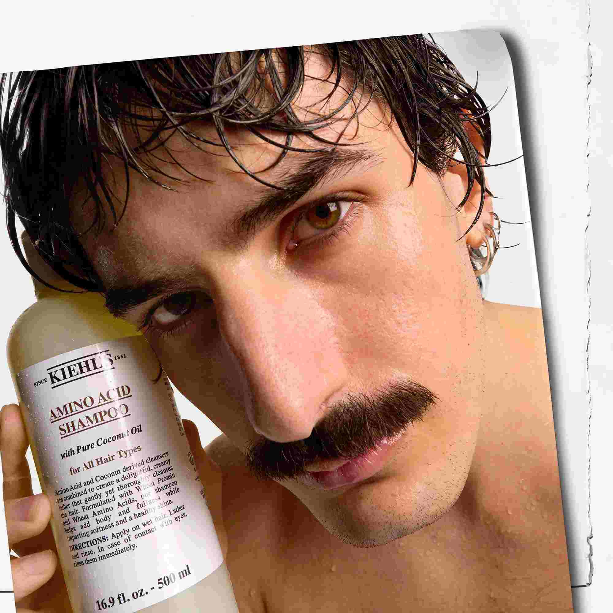 Modelo con bigote y un frasco de champu Amino Acid Shampoo de Kiehl's
