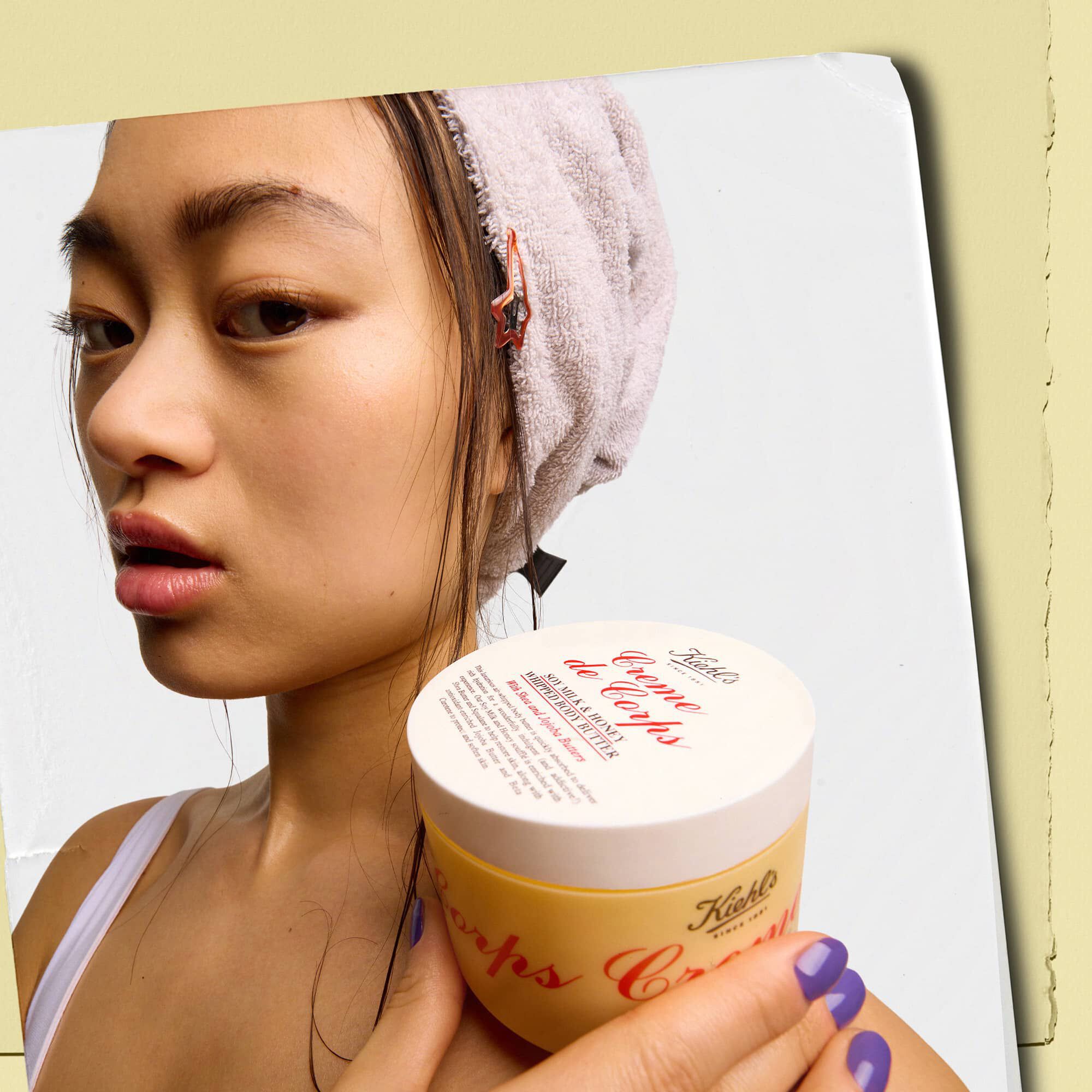 Modelo sosteniendo un tarro de la manteca corporal Kiehl's Creme de Corps Whipped Butter