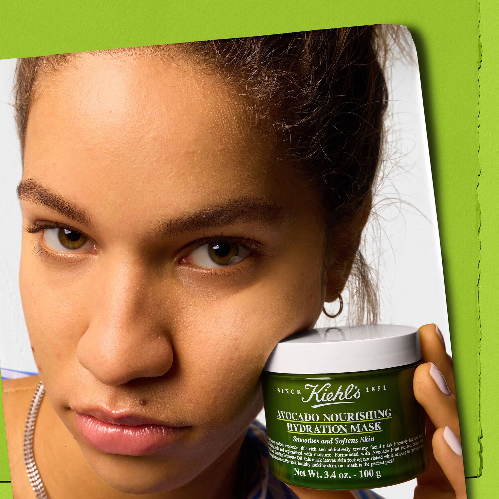 Modelo sosteniendo un tarro de Kiehl's Avocado Nourishing Hydration Mask: alisa y suaviza la piel