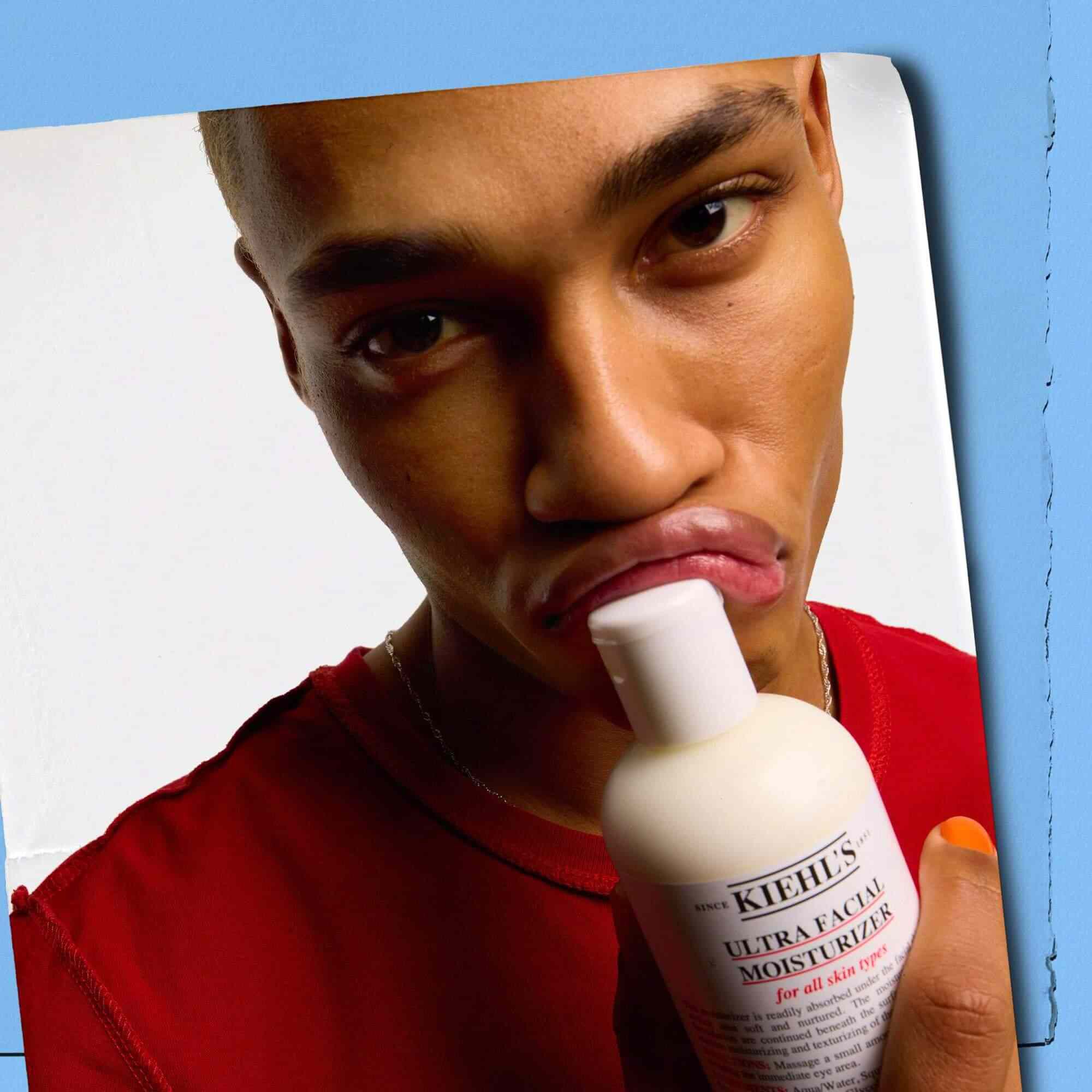 Modelo presionando un frasco de Kiehl's Ultra Facial Moisturizer contra sus labios