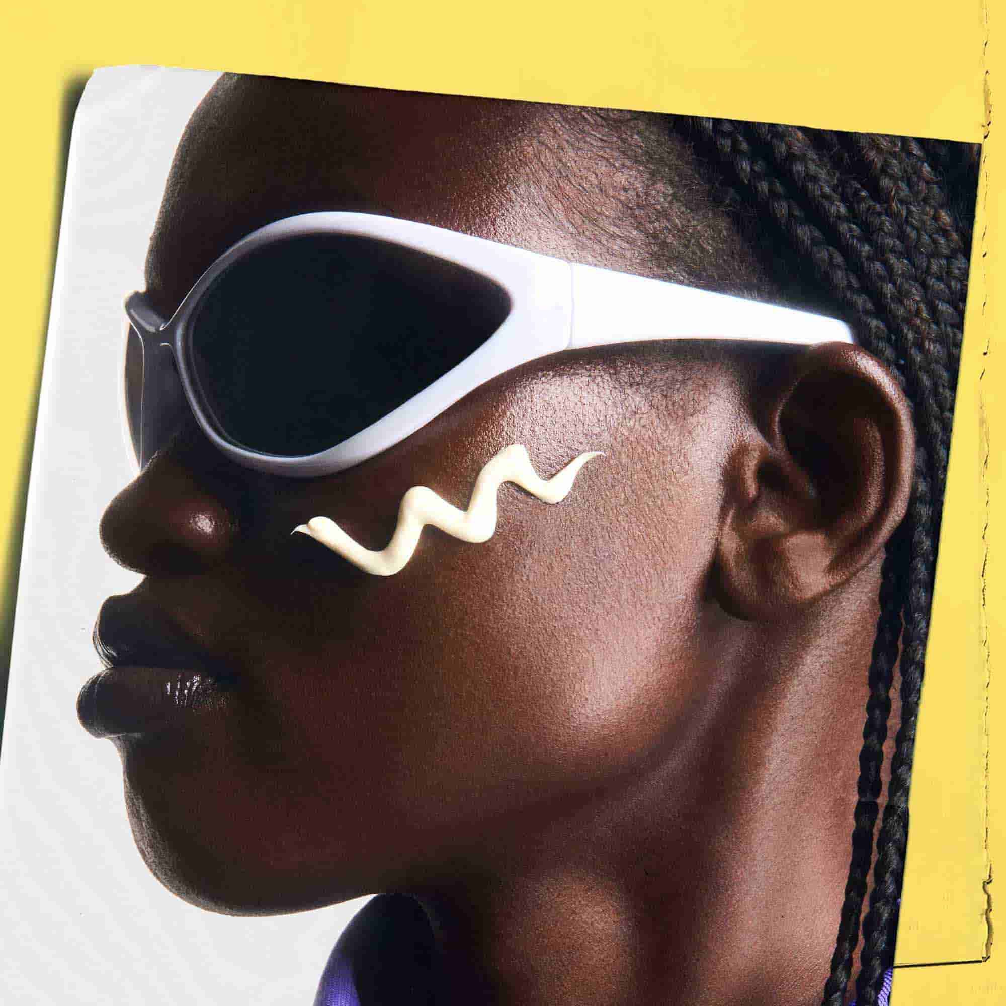 Ultra-Light Daily UV Defense aplicado sobre la piel, mostrando a una persona con gafas de sol.