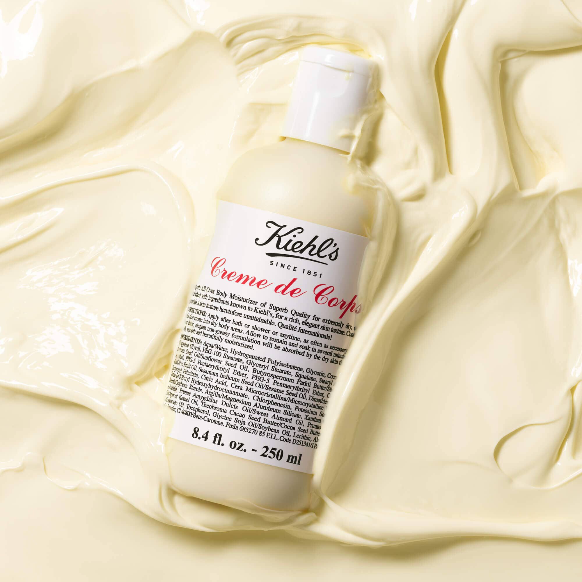 Frasco de Kiehl's Creme de Corps sobre una gran cantidad de locion corporal con textura
