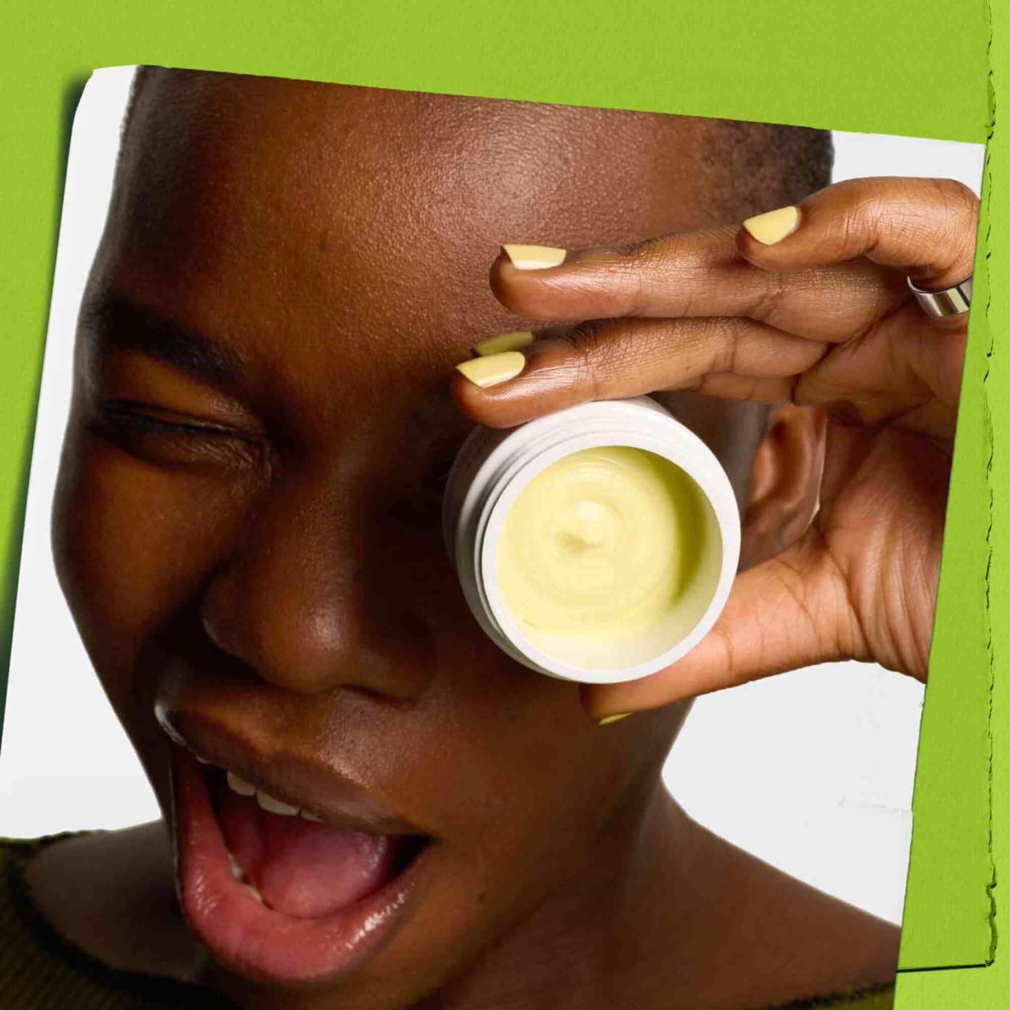 Modelo guinando un ojo con un tarro de Kiehl's Creamy Eye Treatment with Avocado tapando un ojo