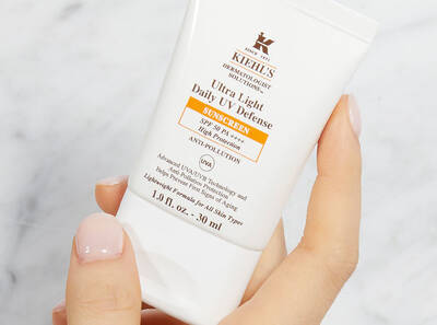 Crema solar ligera de Kiehl's, 30 ml, con proteccion SPF 50 y propiedades antipolucion, sostenida en una mano.