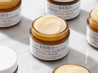 Tarros de crema hidratante de Kiehl's con extracto de flor de calendula, sobre una superficie de marmol.