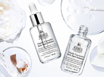 Frascos de suero para el cuidado de la piel de Kiehl's, rodeados de flores blancas y productos de belleza en un fondo minimalista.