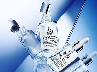 Frascos de suero de Kiehl's para corregir manchas oscuras sobre un fondo azul, resaltando su presentacion elegante y moderna.