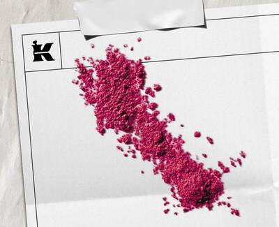 Bright pink powder pigment scattered across white paper packaging featuring the Kiehl’s logo.