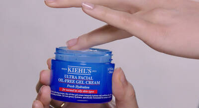 Crema de gel hidratante sin aceite de Kiehl's, con mano aplicando el producto desde un envase azul.