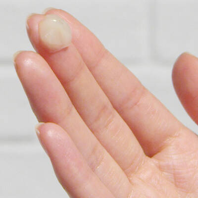 Preparo de crema aplicada en la yema de un dedo, con fondo blanco que resalta la textura del producto.