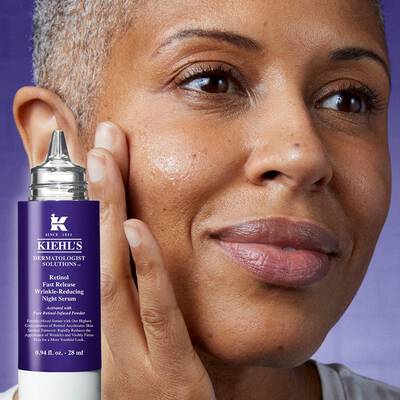 Mujer aplicando suero antienvejecimiento de Kiehl's en la piel del rostro, mostrando una expresion de cuidado y satisfaccion.