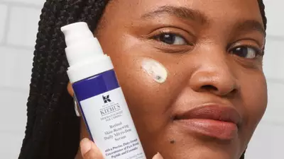 Mujer aplicando suero antienvejecimiento de Kiehl's sobre la piel, mostrando el producto y su textura.