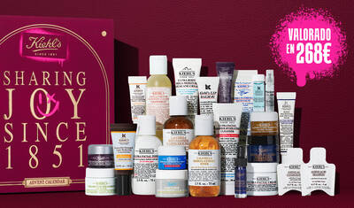 Caja regalo del calendario de Adviento de Kiehl's en rojo intenso con texto dorado, junto a 24 productos miniatura para el cuidado de la piel, entre los que se incluyen la crema Ultra Facial Cream, el tonico Calendula Toner, el serum Retinol Serum y el balsamo labial Lip Balm #1. Un grafico en spray rosa en el lateral destaca el valor del conjunto.