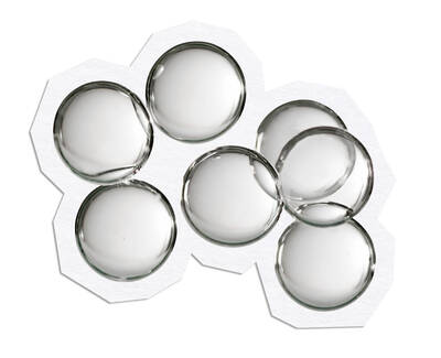 A dropper releasing a drop of liquid into a petri dish, surrounded by several other petri dishes with various colored liquids.