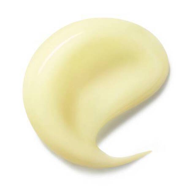 Una pequena gota de una crema o locion de color amarillo claro sobre un fondo blanco.